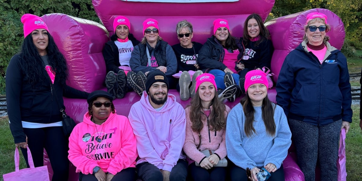 UGI employees dressed in pink sit on large inflatable pink chair at Breast Cancer Awareness walk.